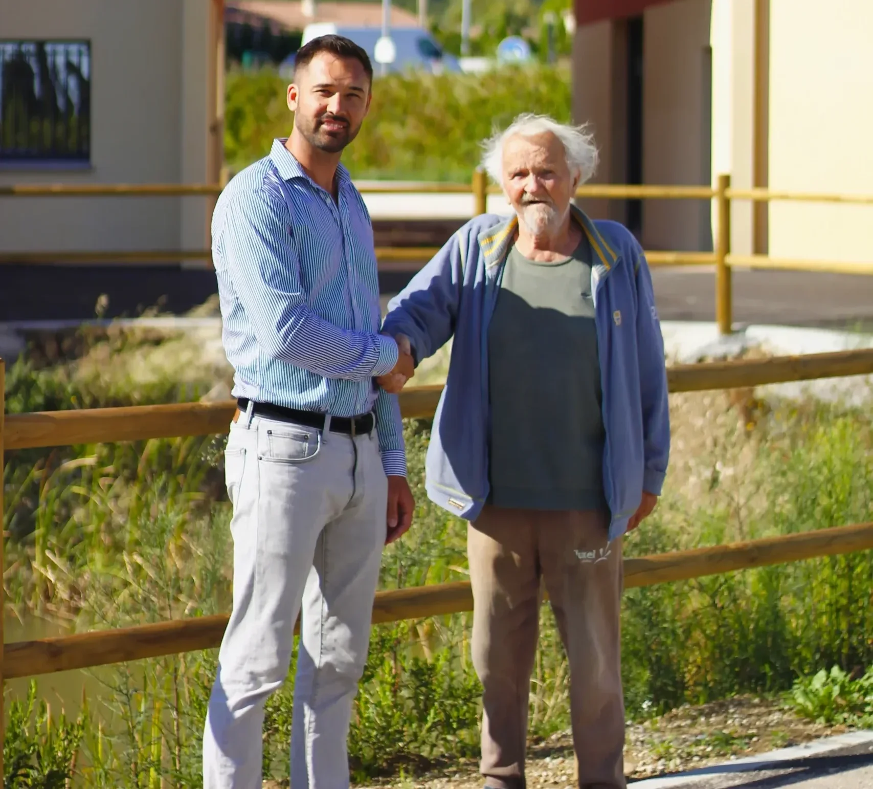 Deux hommes se serrent la main en extérieur, symbolisant une collaboration réussie entre C.O.A et un client satisfait dans un environnement ensoleillé.