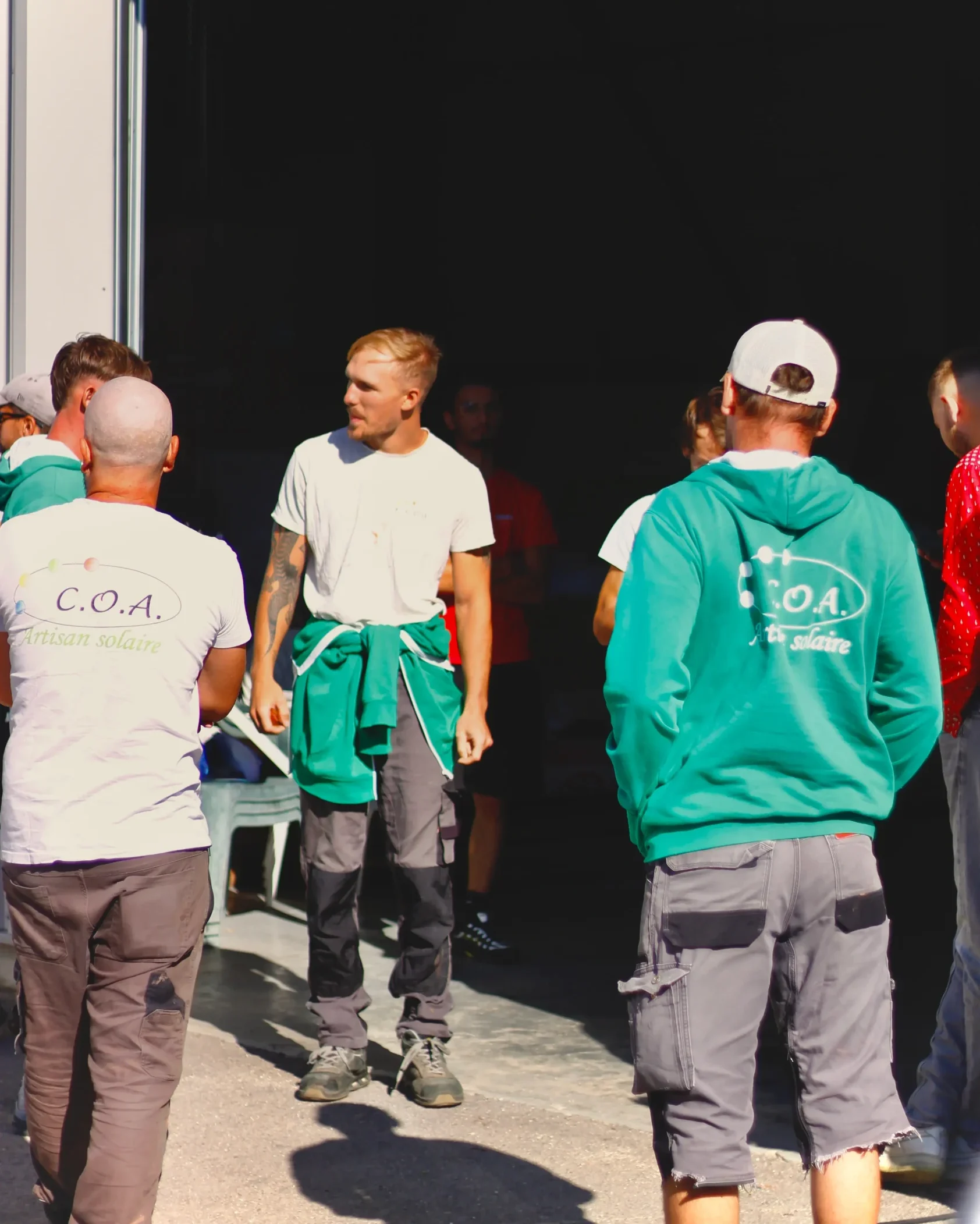 Équipe d’installateurs de panneaux solaires C.O.A en tenue de travail, rassemblée devant l’atelier dans le sud de la France.