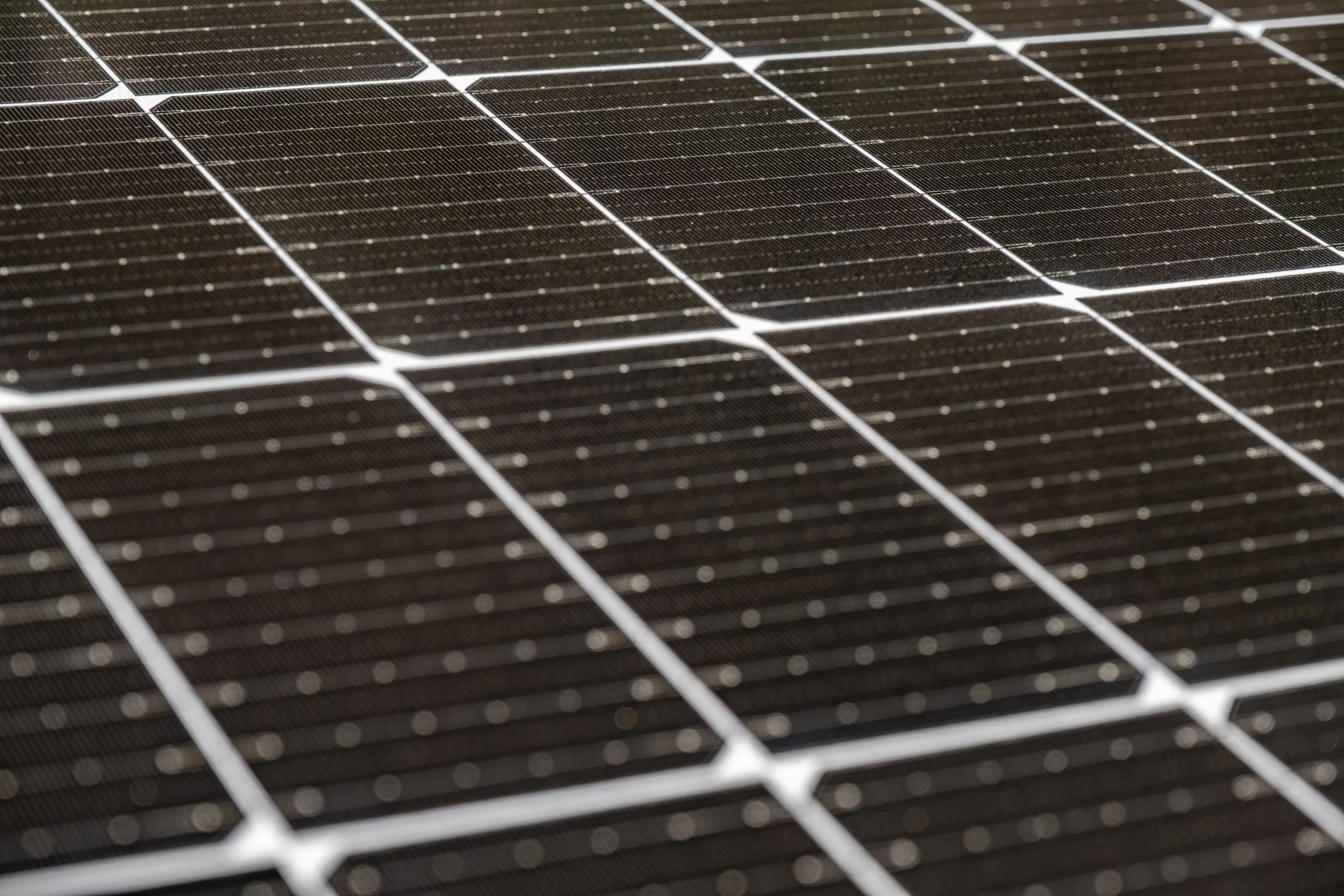 Gros plan sur la surface d’un panneau solaire photovoltaïque montrant les cellules et les lignes de contact.